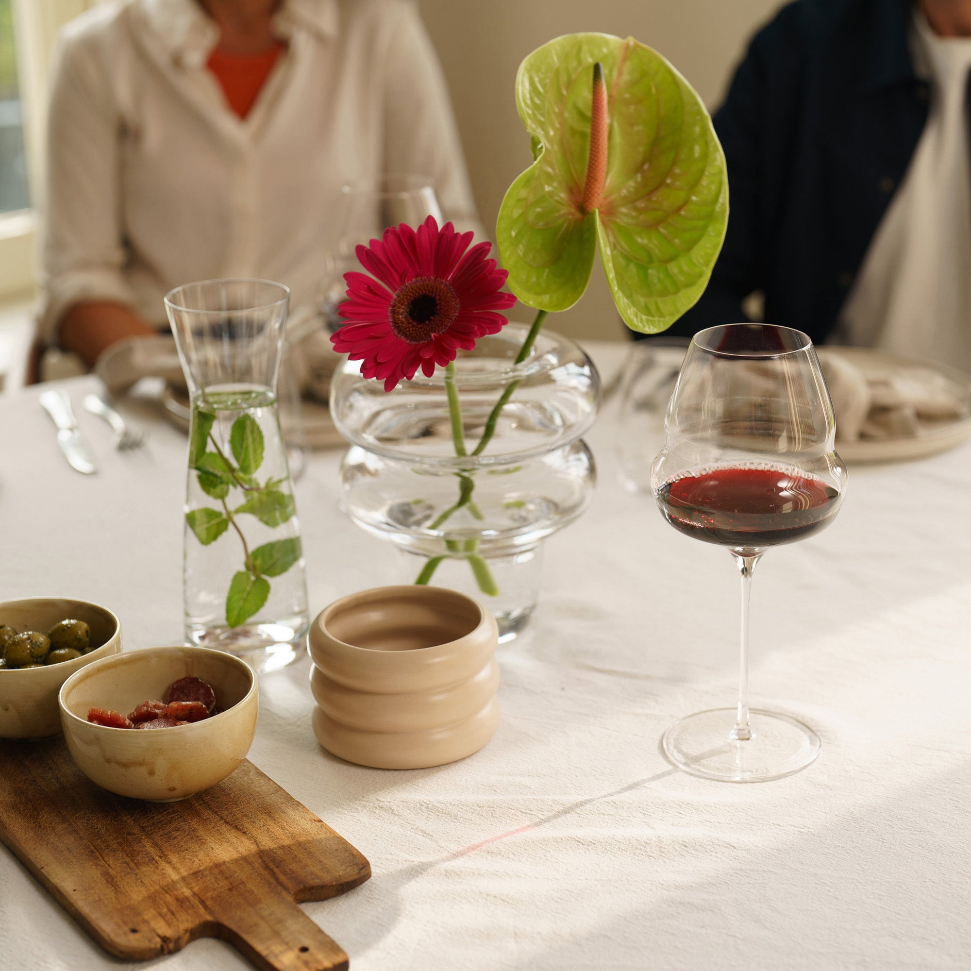 Eleganter Burgunderkelch kaufen auf einem dekorativ gedeckten Tisch mit Blumen und Snacks