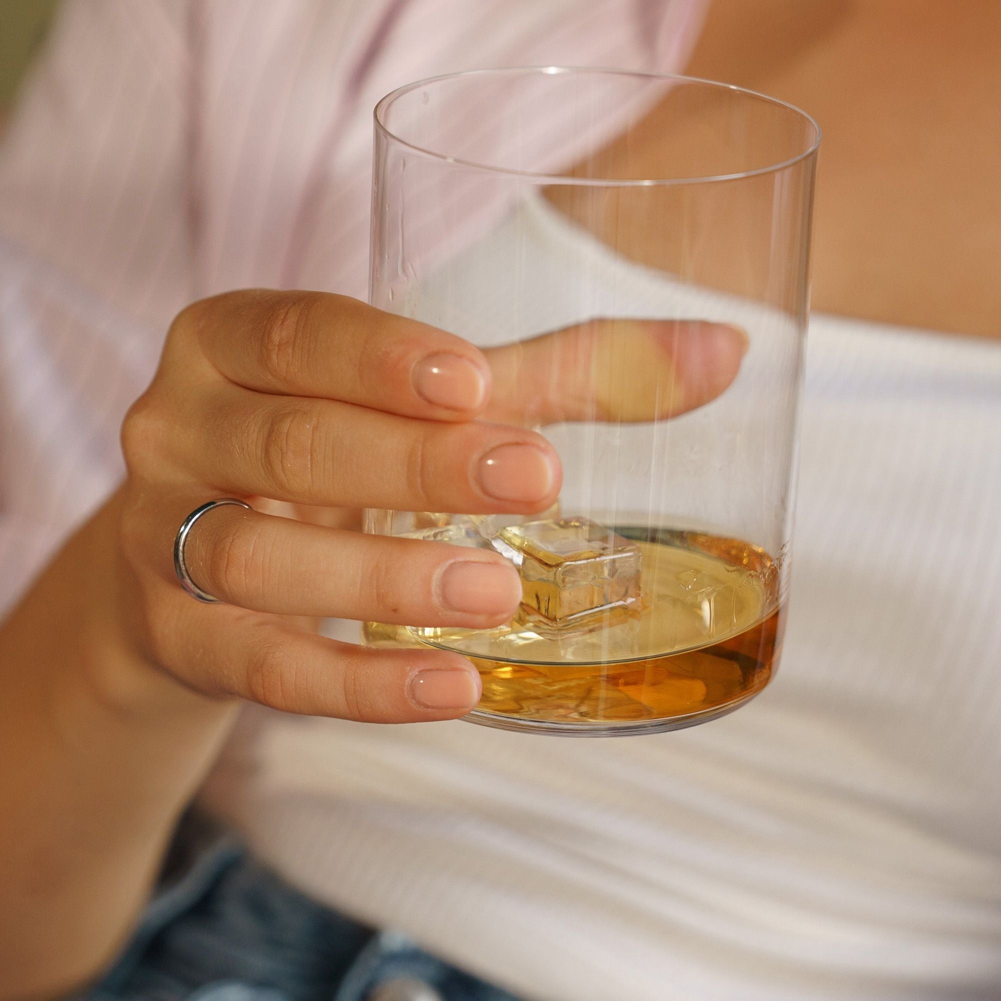 Stölzle Lausitz Whiskyglas aus deutscher Glaskunst mit Whisky und Eiswürfeln in einer Hand