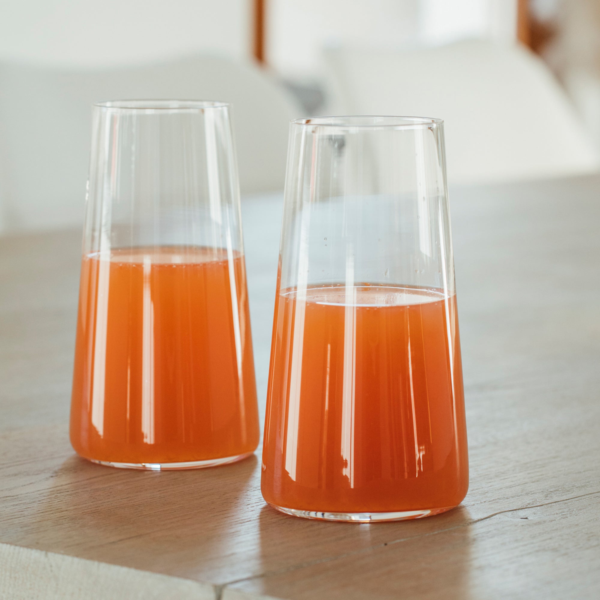 Zwei elegante deutsche Qualitätsgläser Longdrink mit frischem Getränk auf einem Holztisch