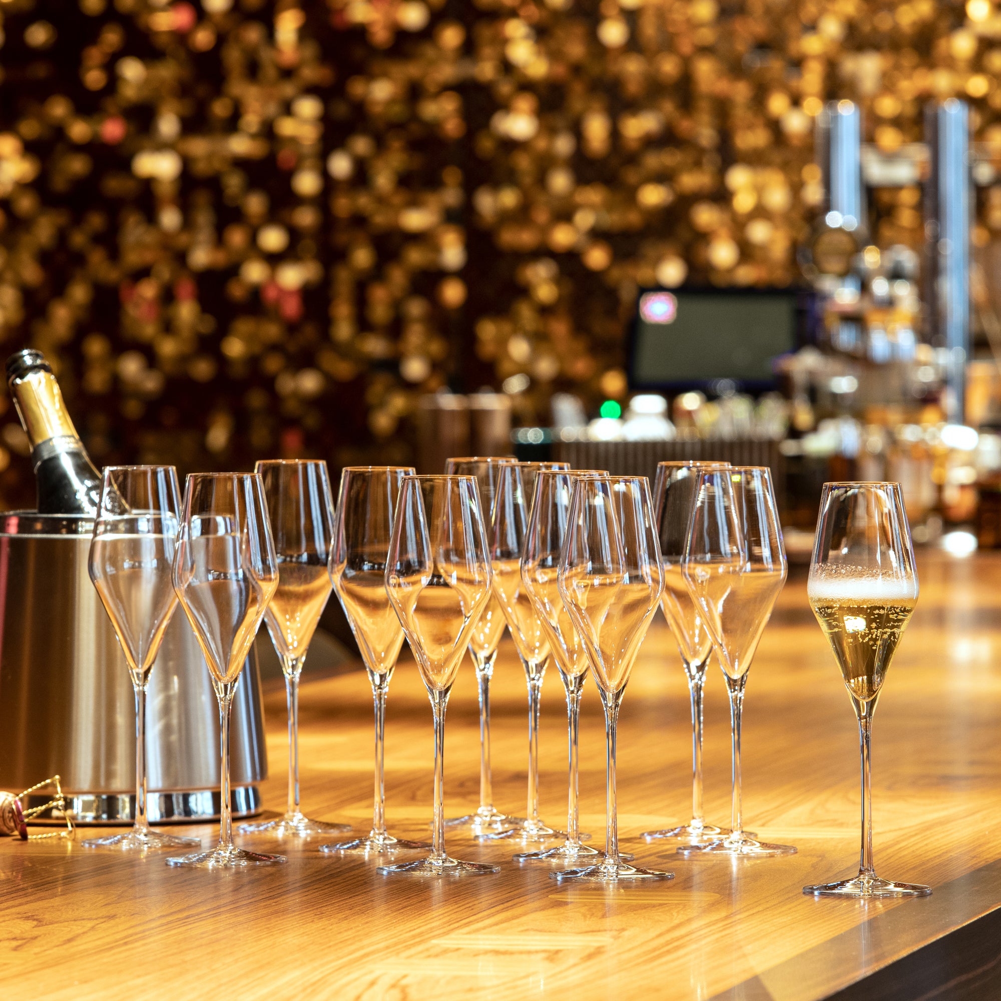 Elegante exklusive Champagnergläser auf einer Holztheke mit Champagnerflasche im Hintergrund