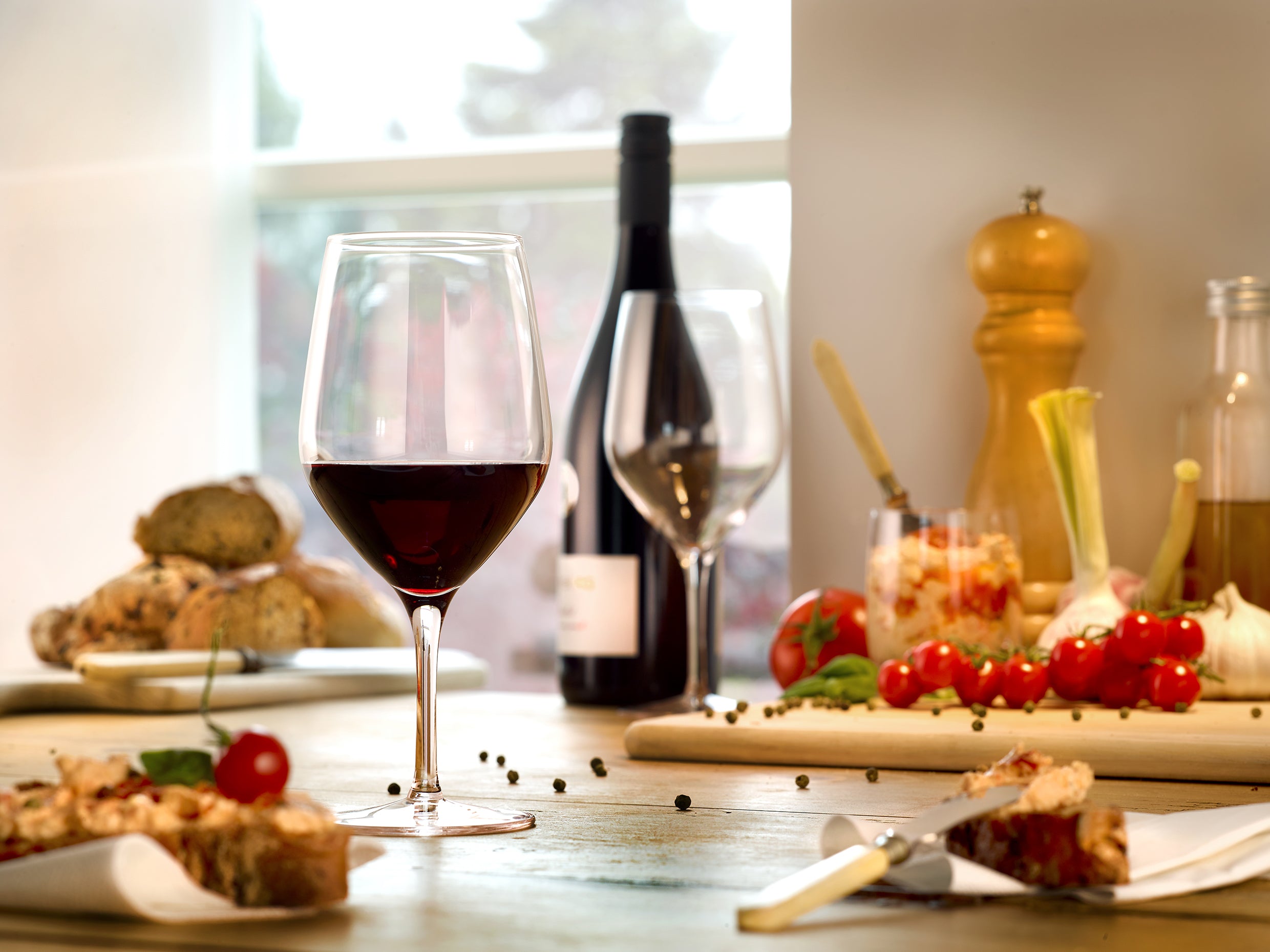 Hochwertige Bordeauxgläser in eleganter Umgebung mit Rotwein und appetitlichen Snacks auf dem Tisch