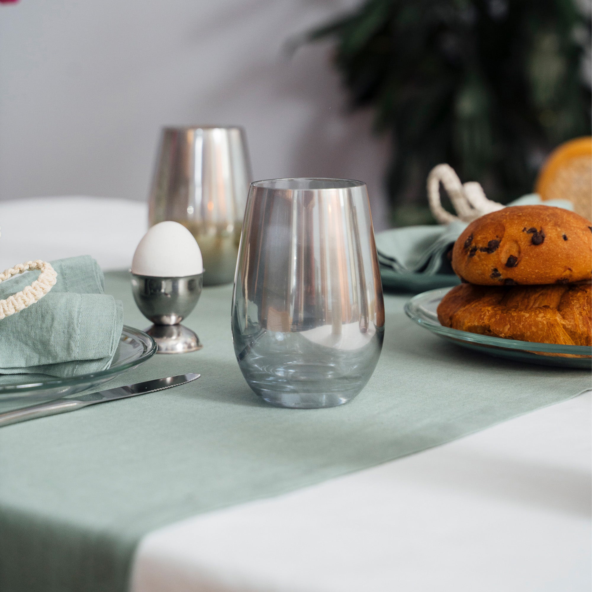 Hochwertige Gläser Made in Germany auf einem elegant gedeckten Tisch neben Brötchen und einem Eierbecher
