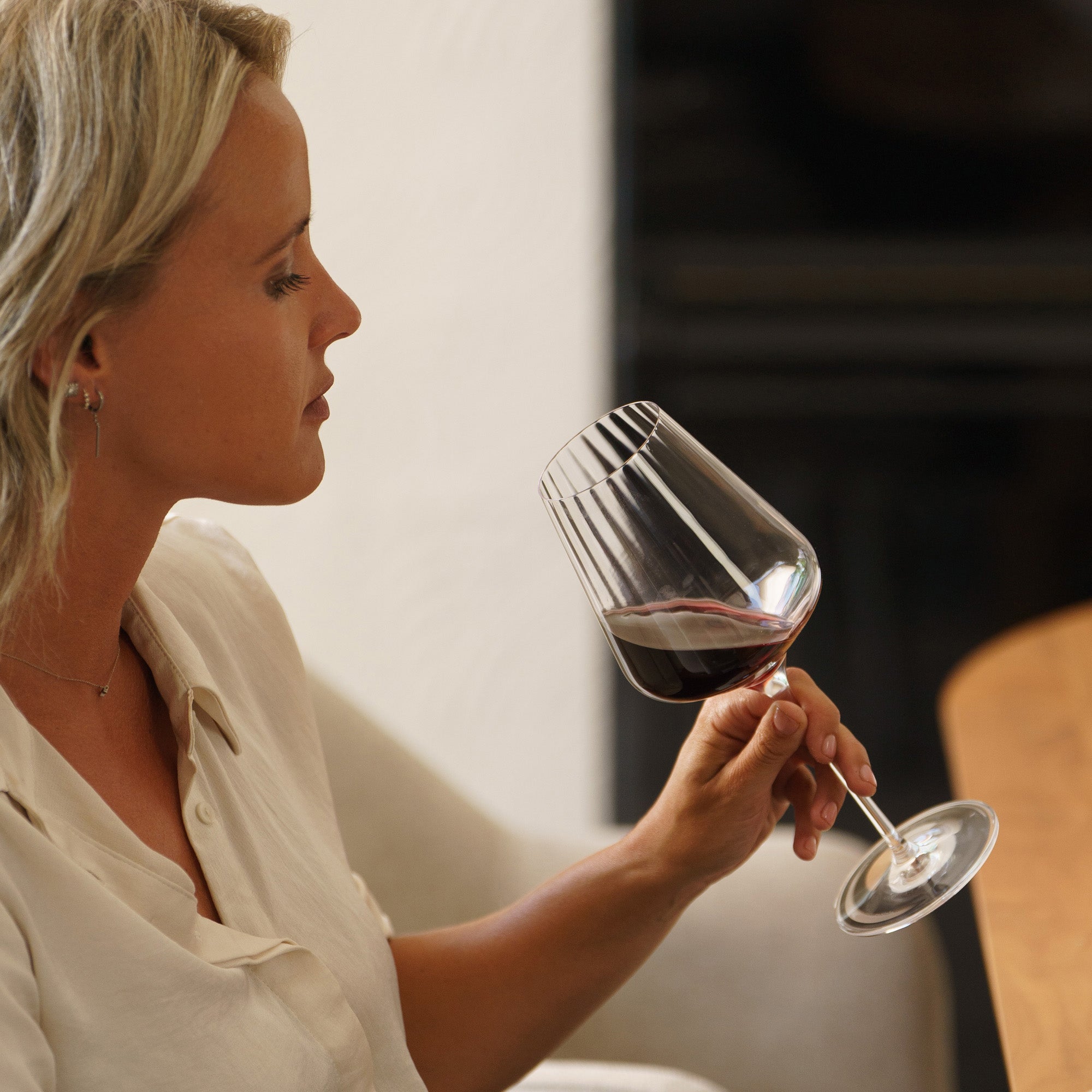 Frau genießt hochwertigen Rotweinkelche bei einem entspannten Abendessen mit Rotwein