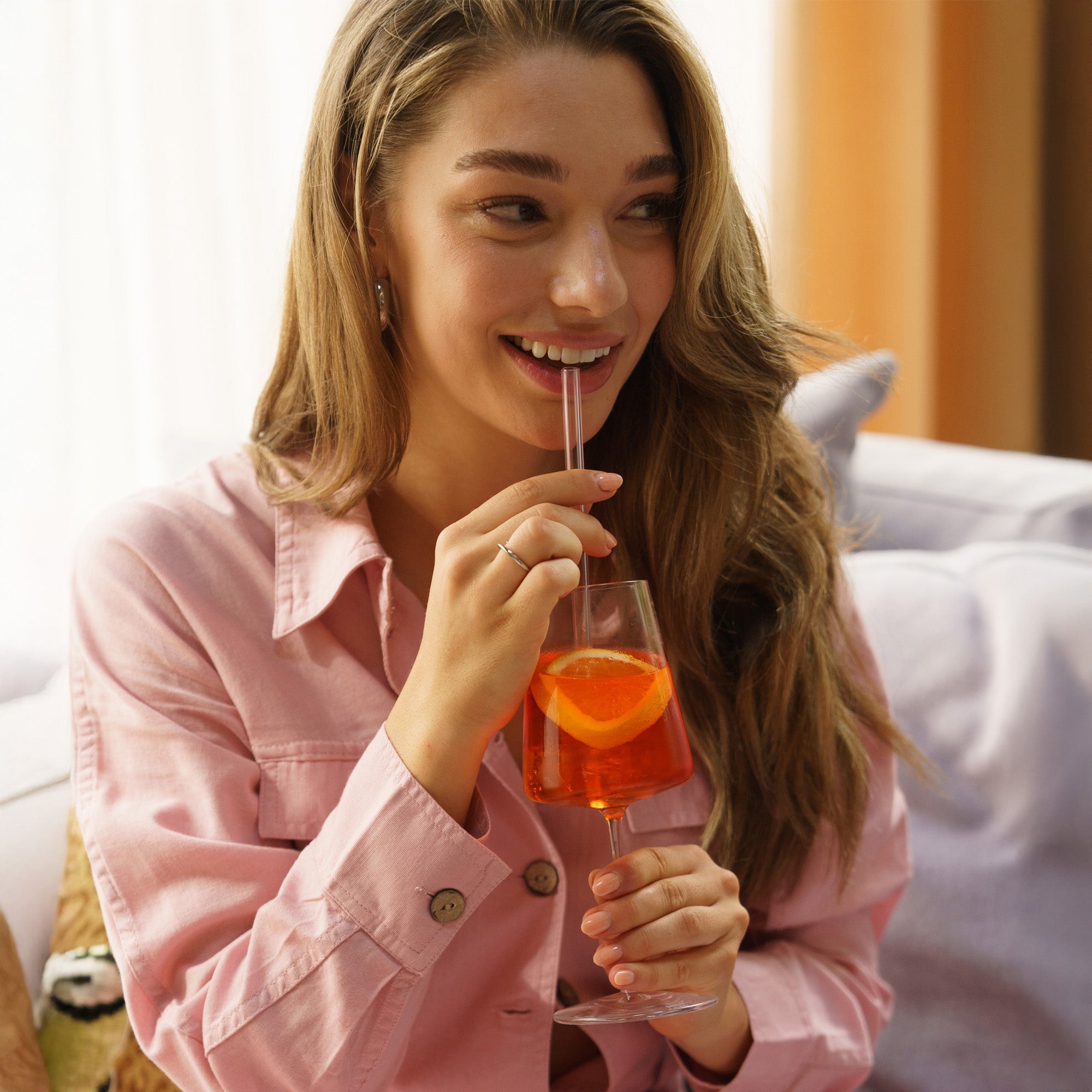 Schöne Frau mit hochwertigem Weinglas, genießt einen erfrischenden Cocktail mit einer Orangenscheibe