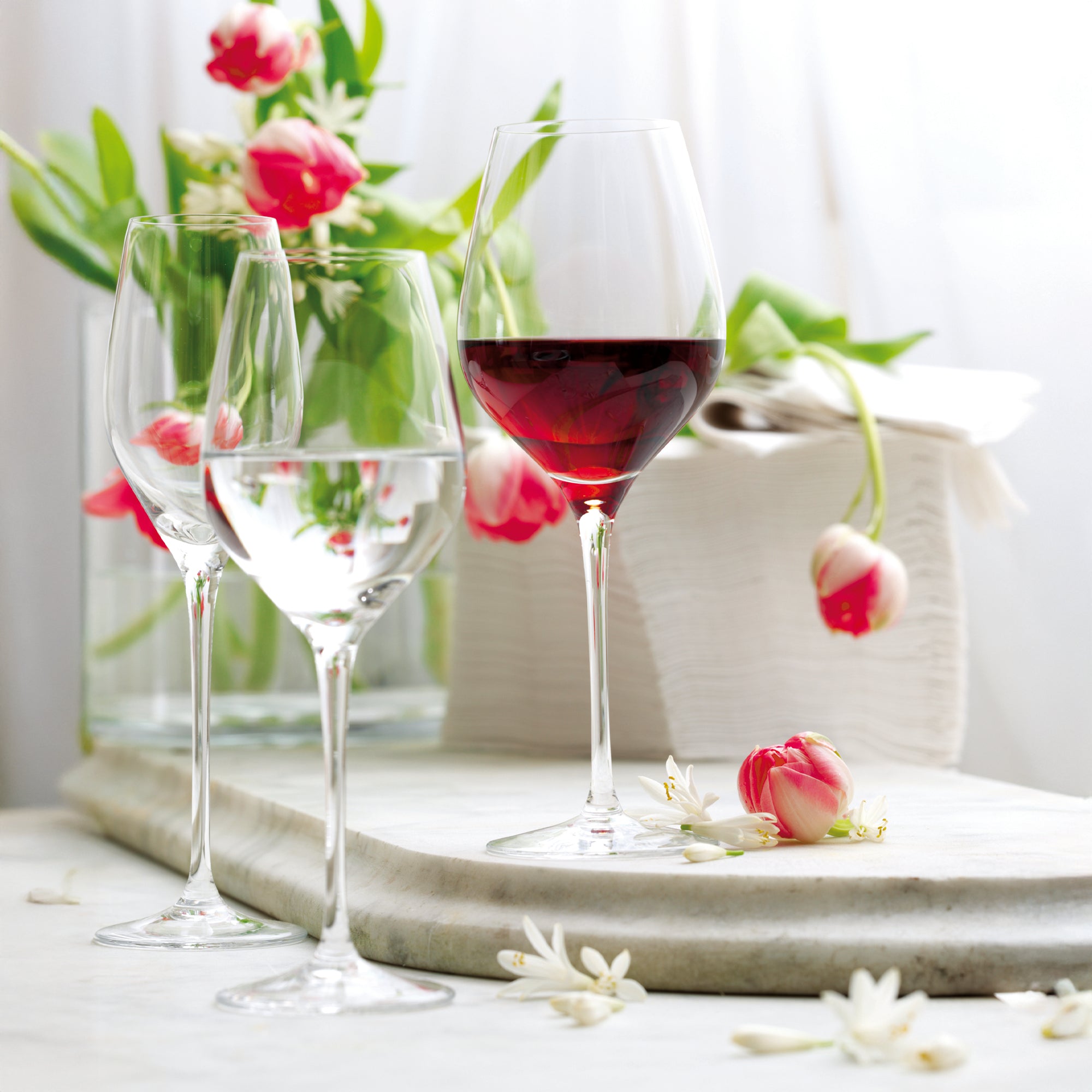 Hochwertige Weingläser Stölzle Lausitz mit Rot- und Weißwein, dekoriert mit Blumenarrangement