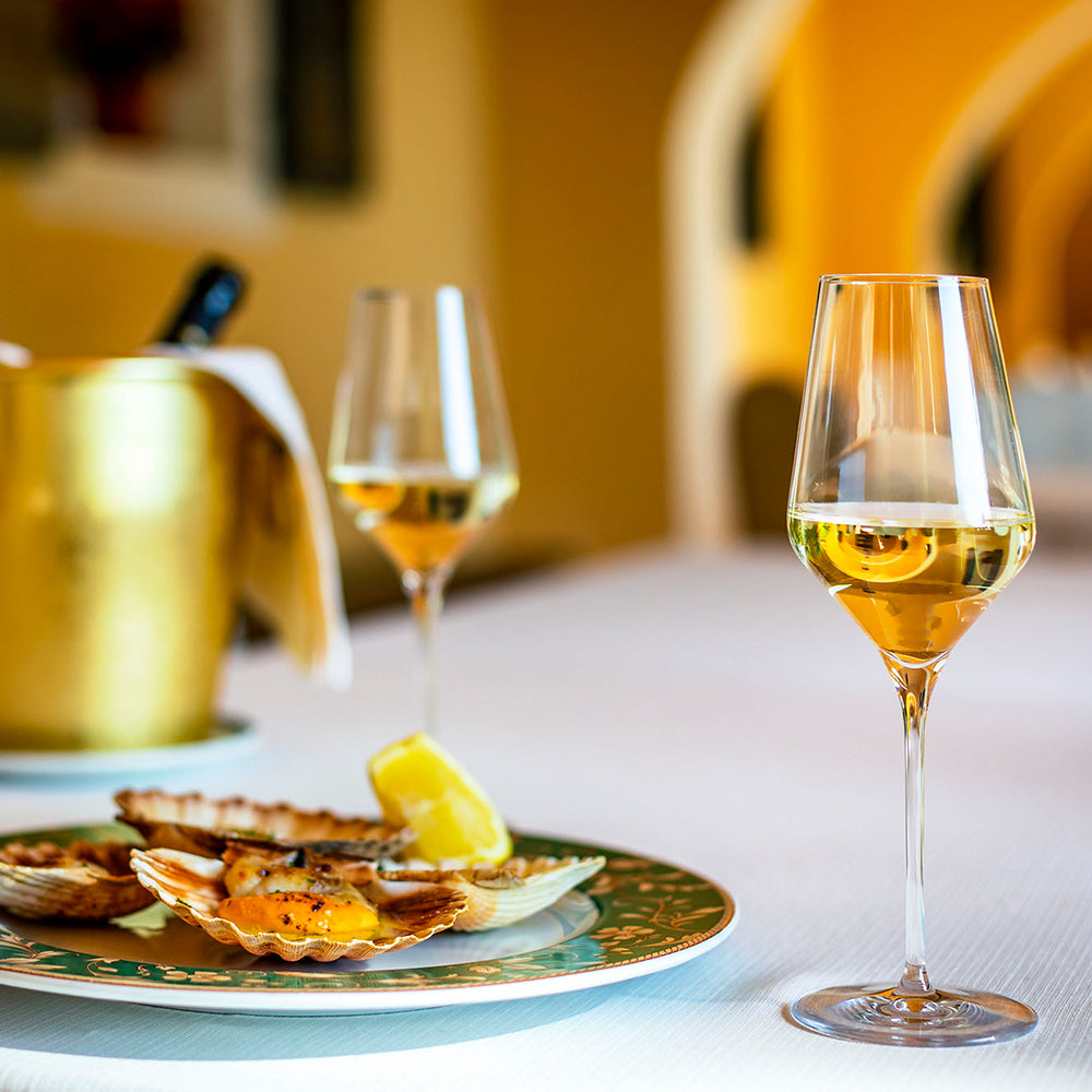 Hochwertige Weißweingläser auf einem Tisch mit herzhafter Meeresfrüchteplatte und einem Champagnerkühler