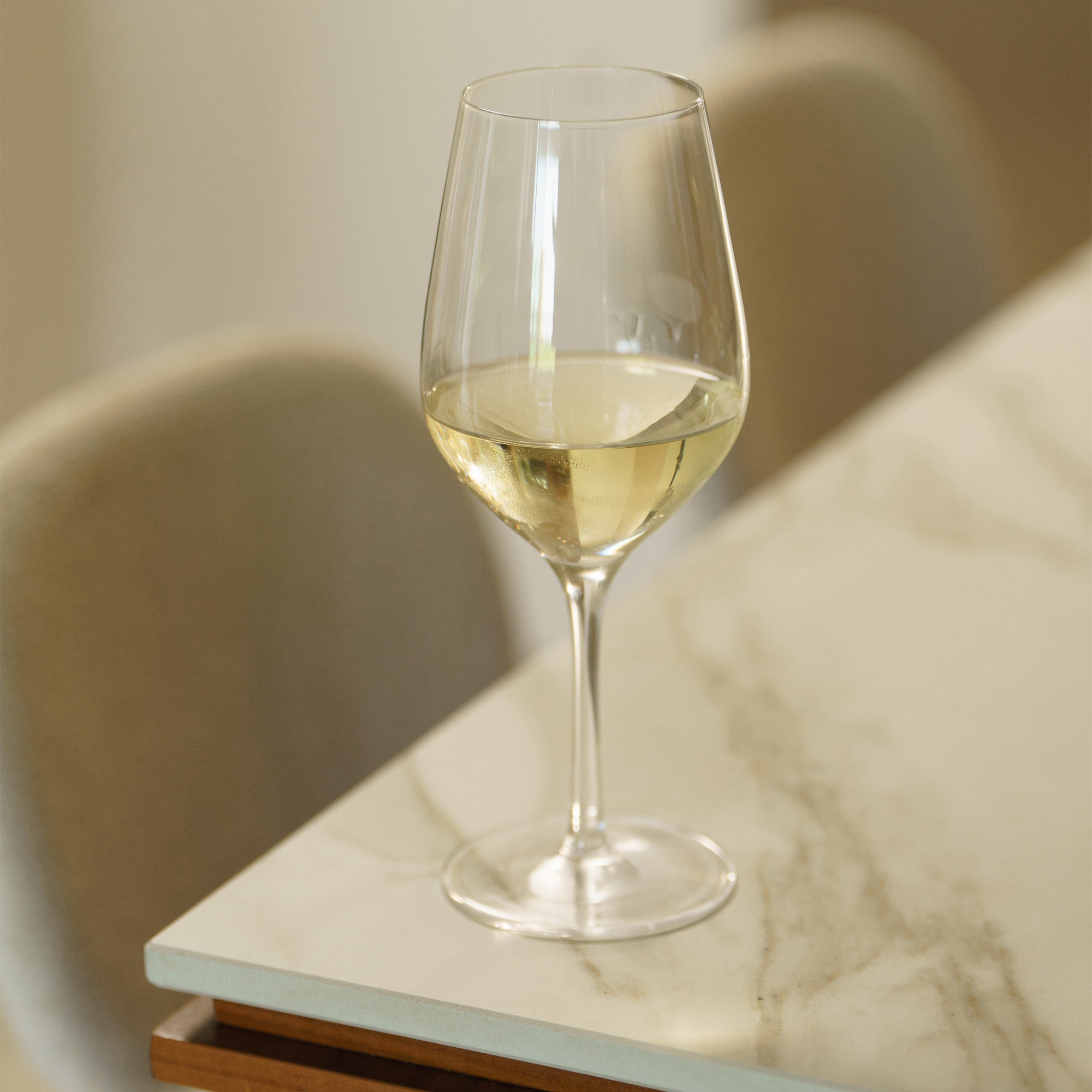Hochwertige Weißweinkelche auf einem Marmor Tisch, gefüllt mit frischem Weißwein.