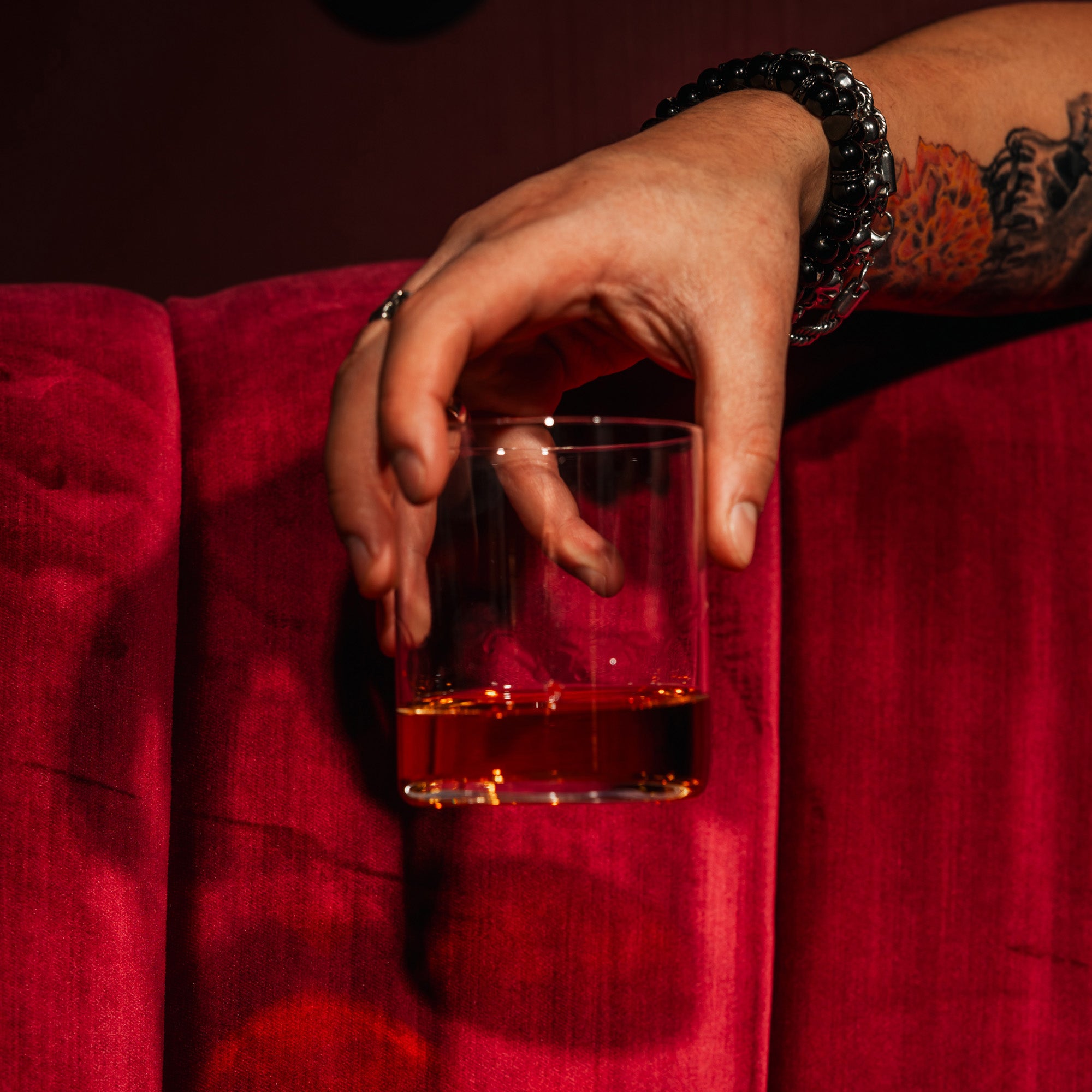 Kyoto Bar Whiskygläser mit einem handgehaltenen Glas Whisky auf rotem Samtsofa