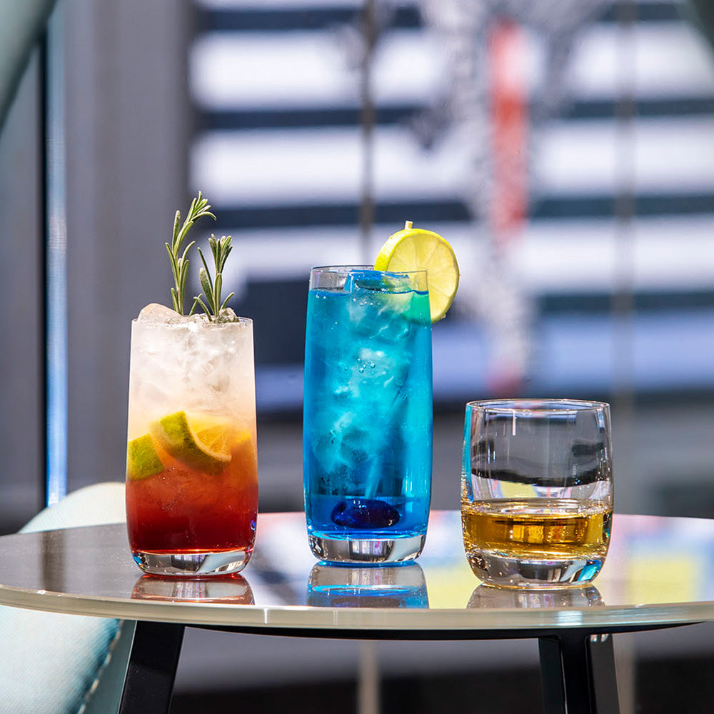 Drei langlebige Trinkgläser mit bunten Cocktails auf einem Tisch, ideal für besondere Anlässe