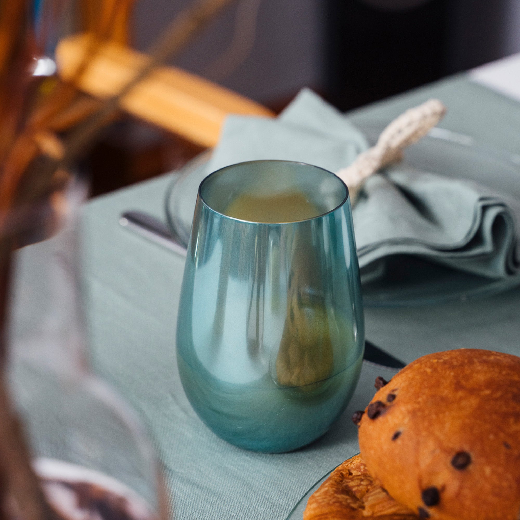 Stölzle Lausitz Longdrinkbecher türkis auf einem Tisch mit Gebäck und Serviette
