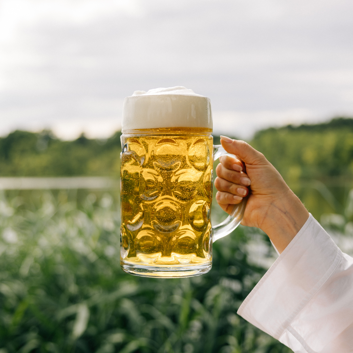Oberglas Isar Bierkrug 1000ml, gefüllt mit Bier in einer weiblichen Hand in der Natur