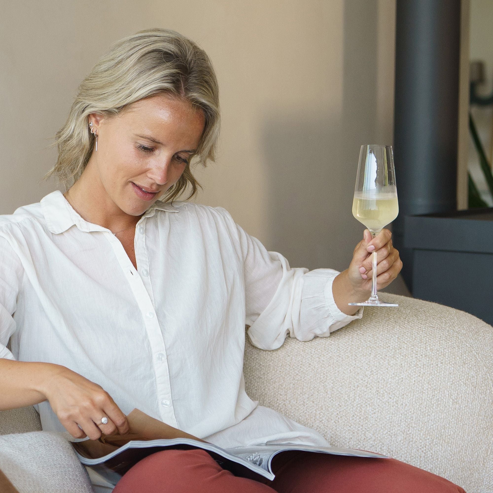Frau entspannt mit STARlight Champagnergläsern und einem Magazin in einem modernen Wohnzimmer