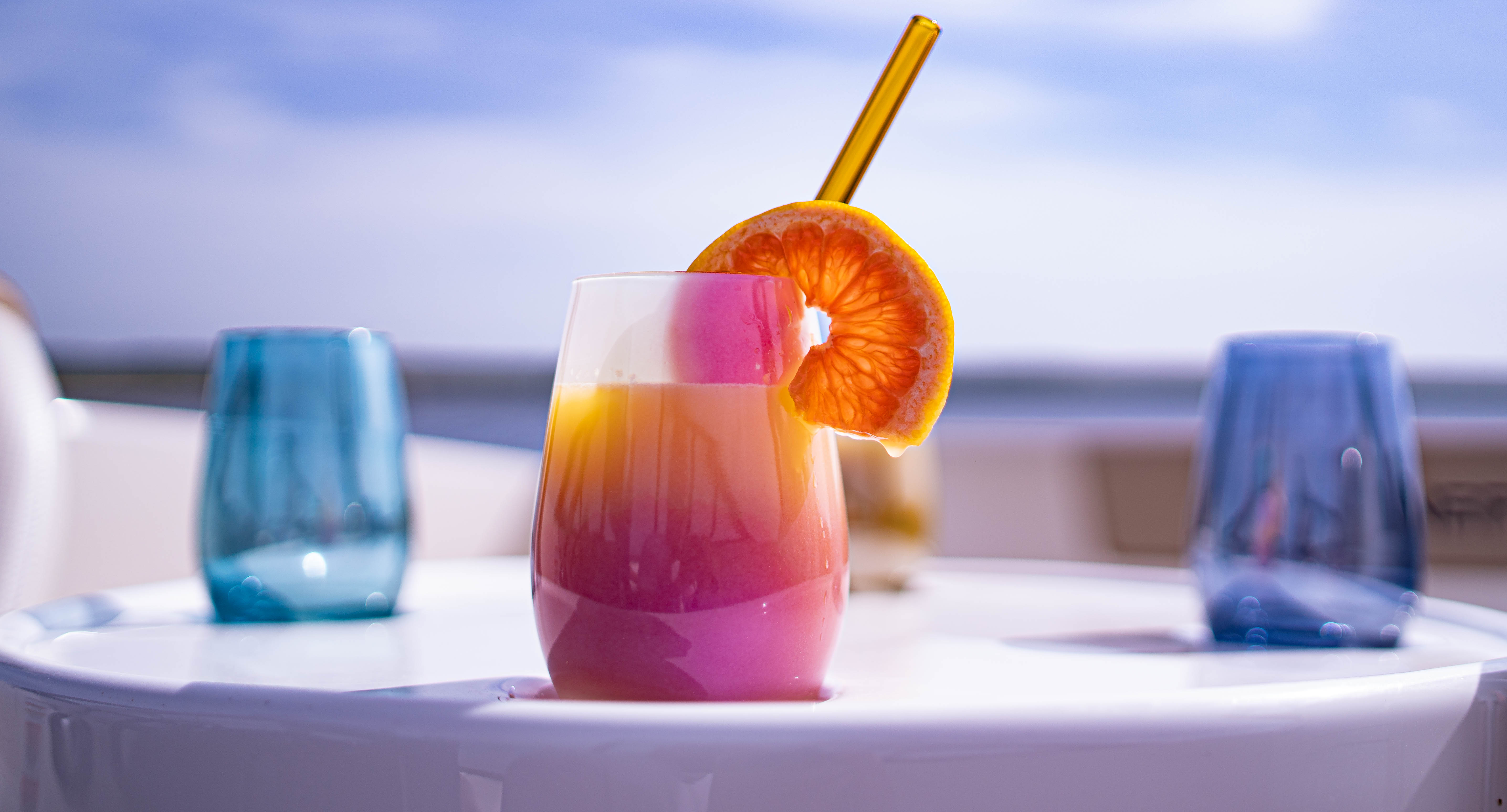 Violette Trinkgläser kaufen auf einem Tisch mit bunten Cocktails und Zitrusfrüchten
