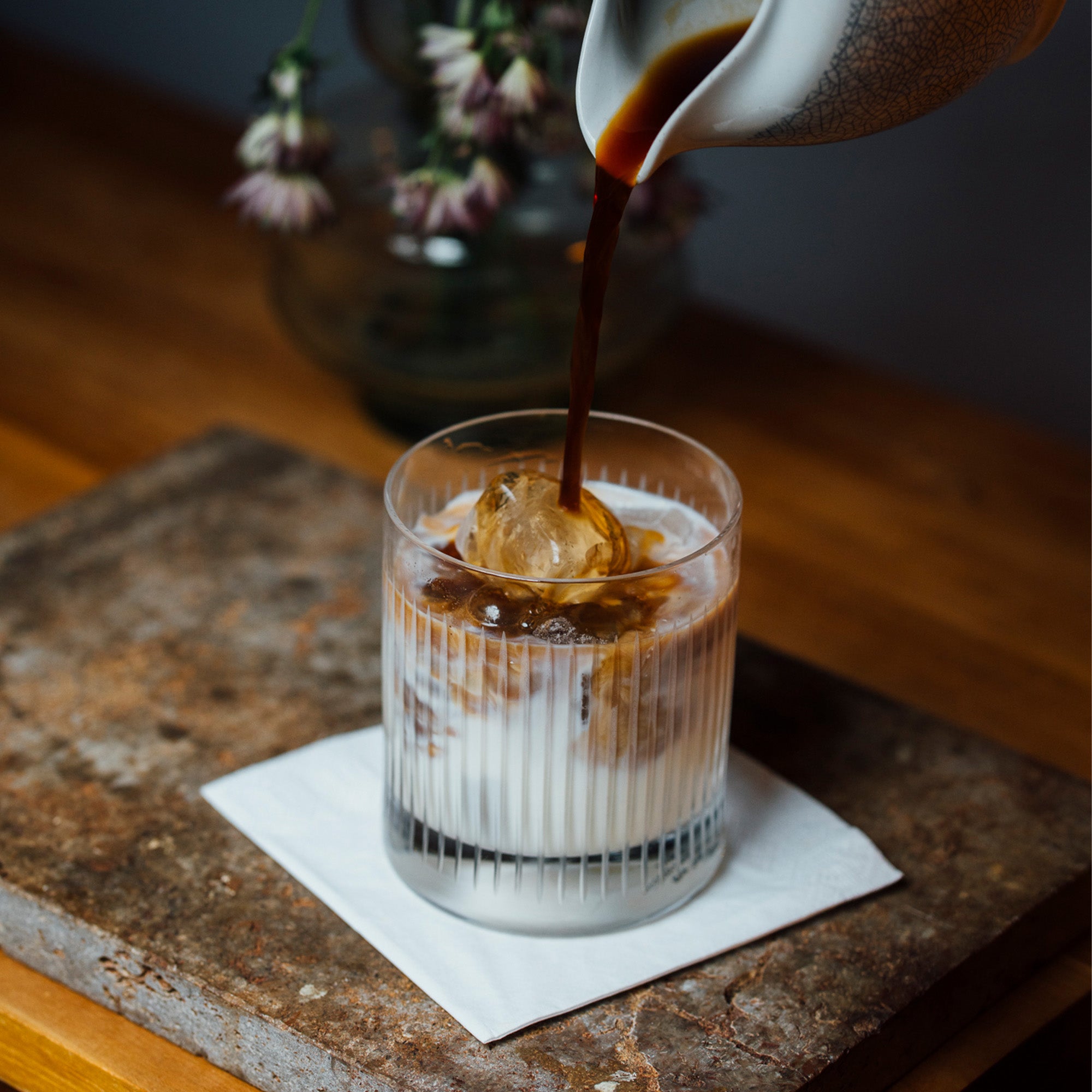 Edle Gläser für Whisky mit eisgekühltem Getränk und Zutatenguss auf einem Holztablett