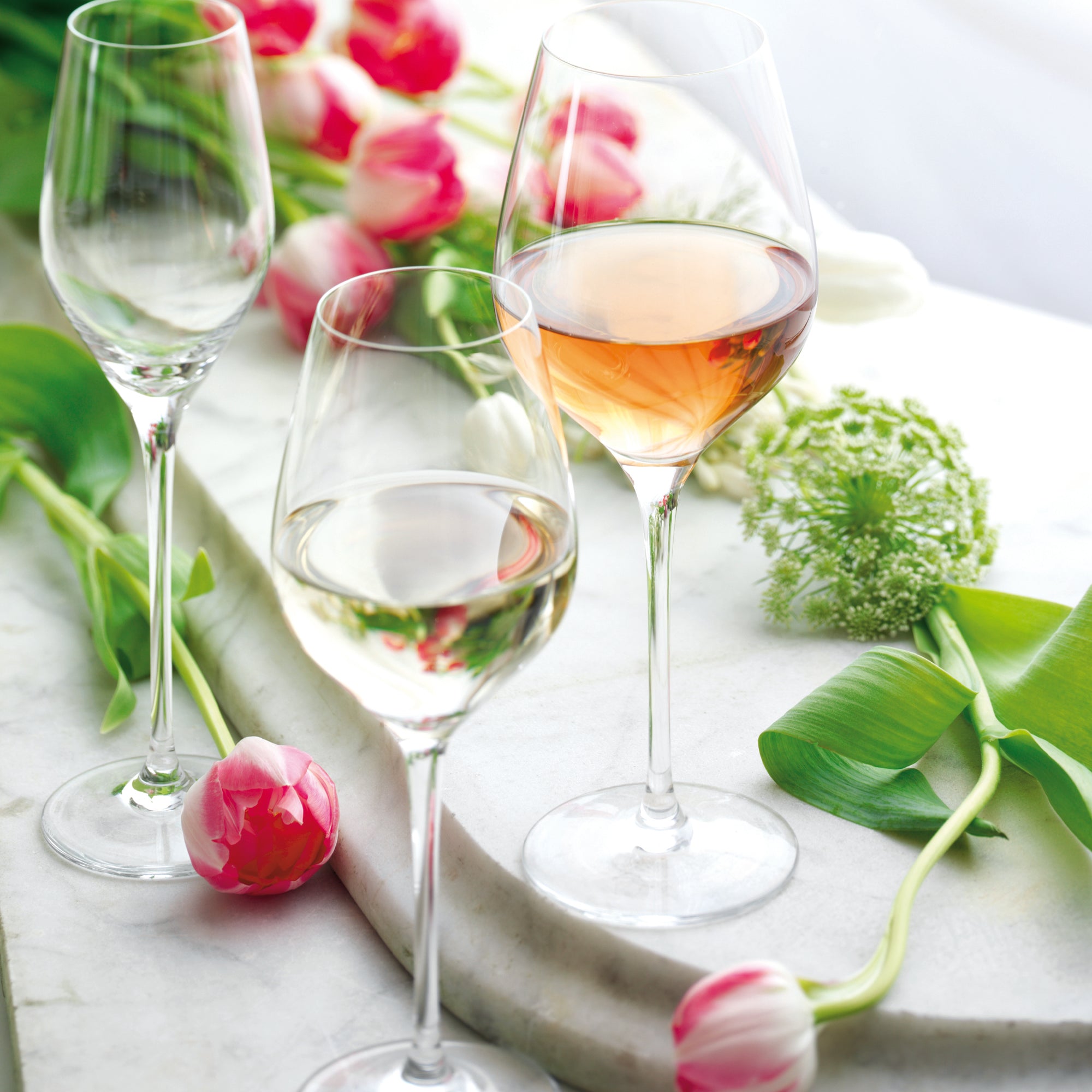 Exklusives Champagner Set mit eleganten Gläsern auf einem Marmoruntergrund, umgeben von Blumenarrangements