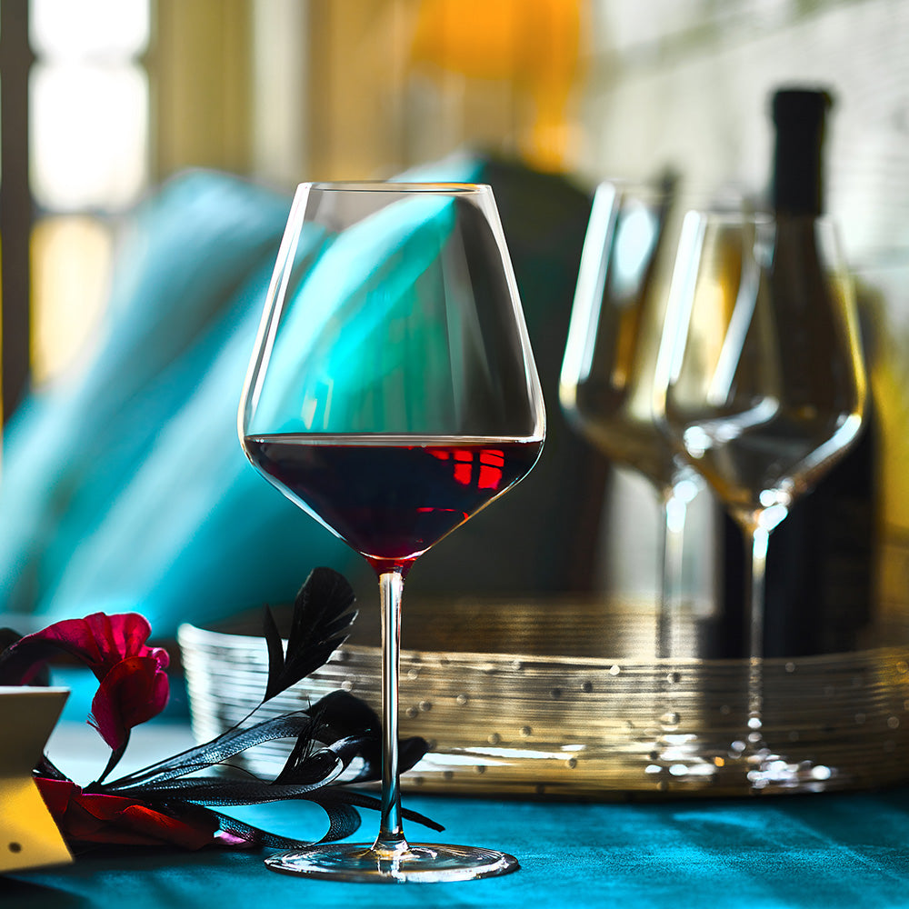 Eleganter hochwertiger Burgunderkelch mit tiefrotem Wein auf einem festlich gedeckten Tisch