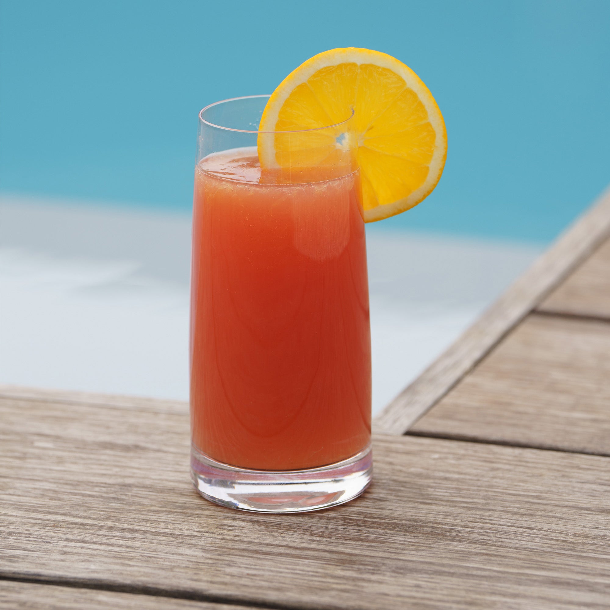 Kleine Longdrinkgläser kaufen mit einem fruchtigen Cocktail und einer Orangenscheibe am Pool.