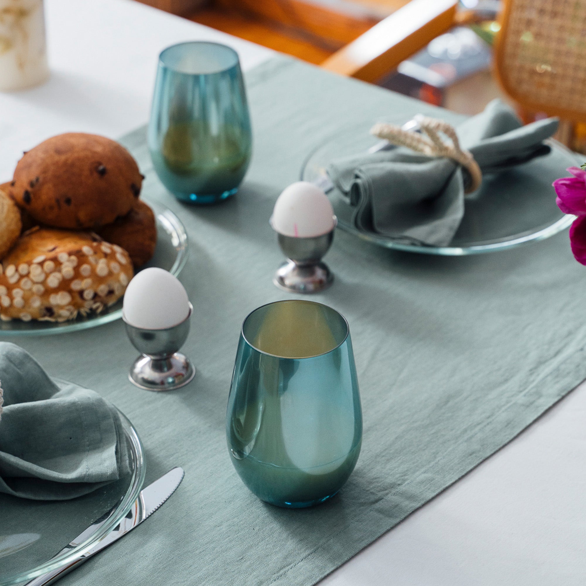 Elegante Longdrinkbecher türkis auf einem hübsch gedeckten Tisch mit Brötchen und Eiern