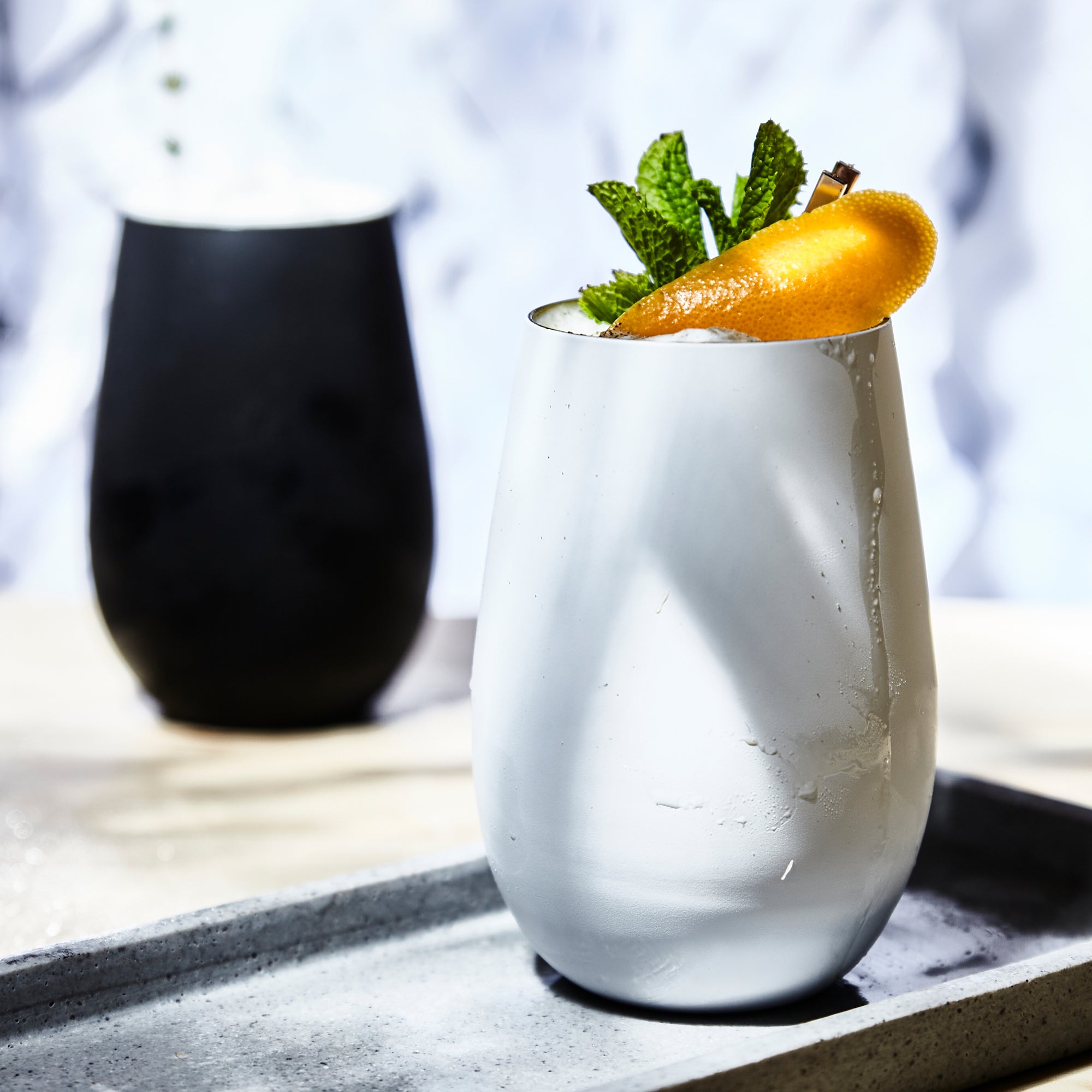 Moderne Becher schwarz gold aus Glas mit elegantem Design und frischem Getränk mit Minze und Zitrusfrüchten