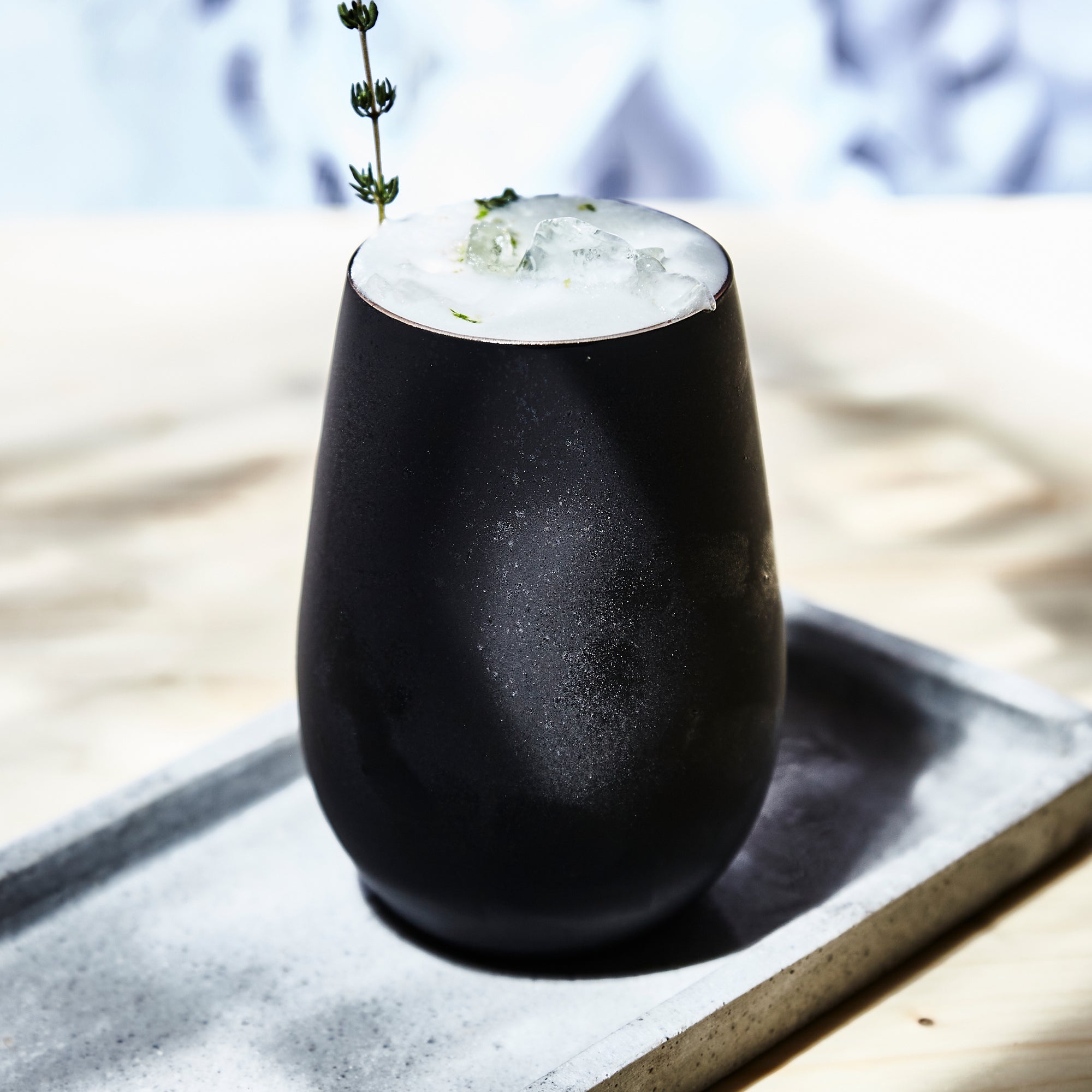 Moderne Becher schwarz gold mit glatter Oberfläche und frischem Getränk auf einem Tablett