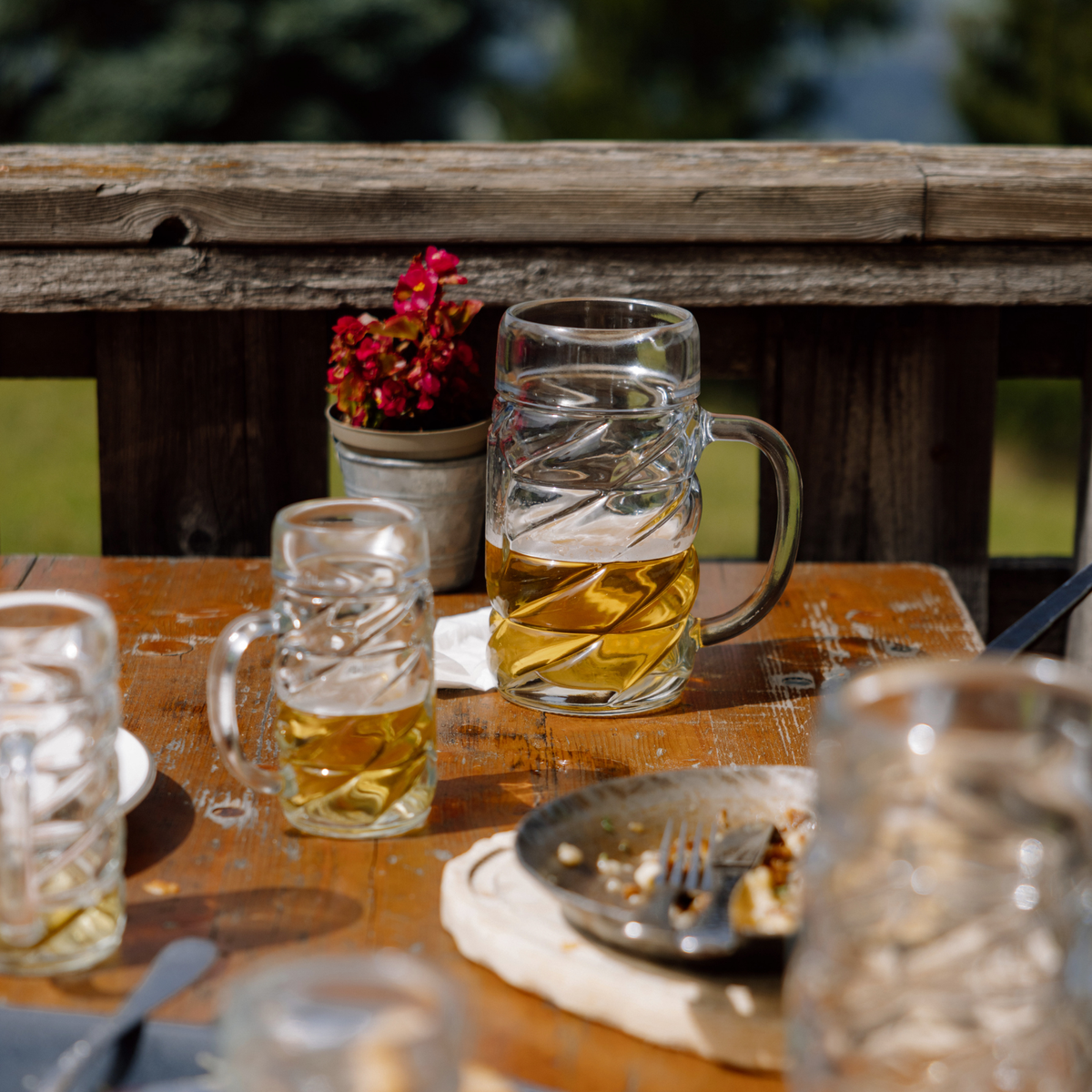 Oberglas Diamond Bierkrug mit Dekorfläche 1000ml, halbgefüllt auf gedecktem Tisch im Biergarten