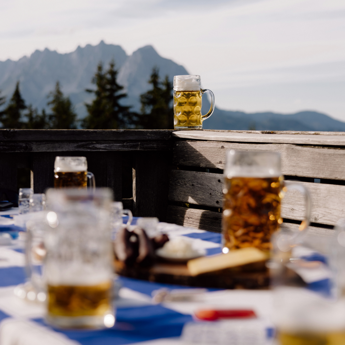 Oberglas Isar Bierkrug 500ml, gefüllt mit Bier auf einem Holzzaun im Hintergrund Berge