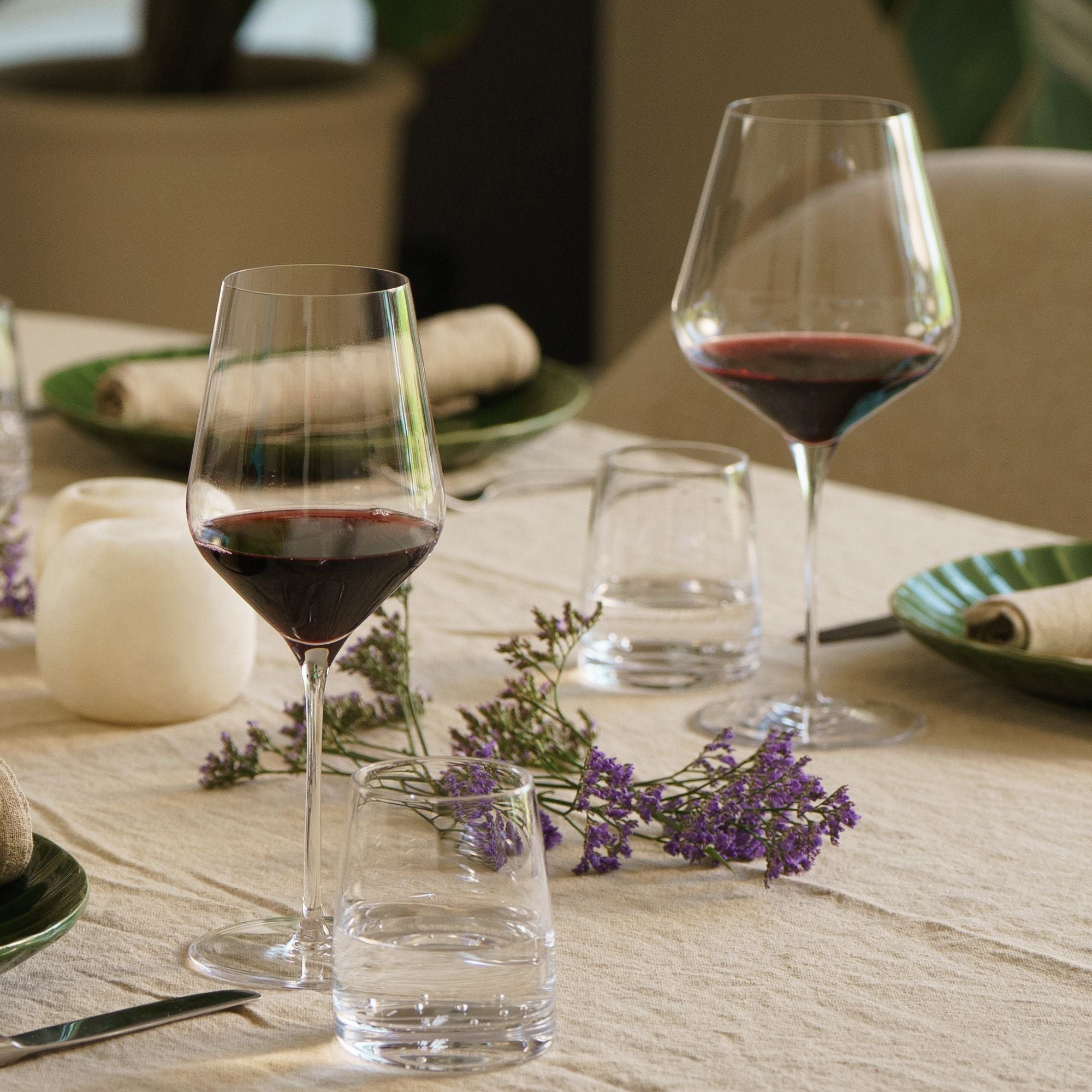 Elegante STARlight Weingläser auf einem festlich gedeckten Tisch mit Rotwein und Blumen