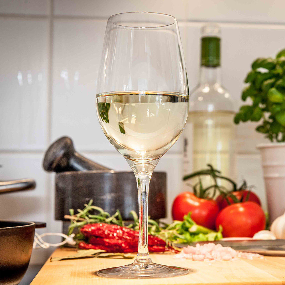 Stölzle Lausitz Gläser in eleganter Form mit Weißwein vor frischen Zutaten in einer modernen Küche