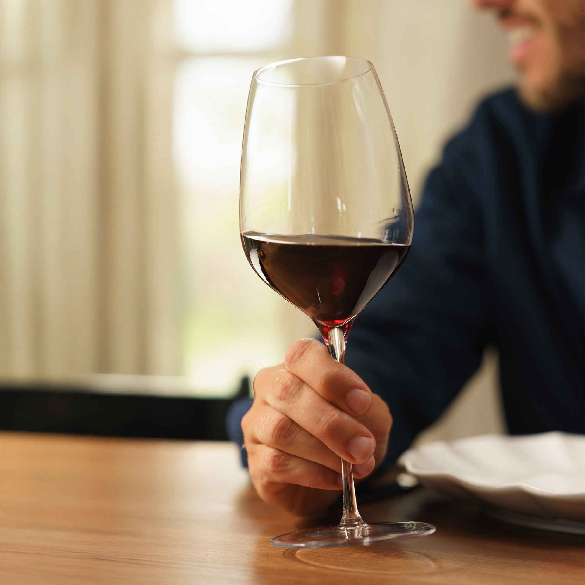 Elegantes Stölzle Lausitz Wein Genussgläser in Hand mit Rotwein auf einem Tisch