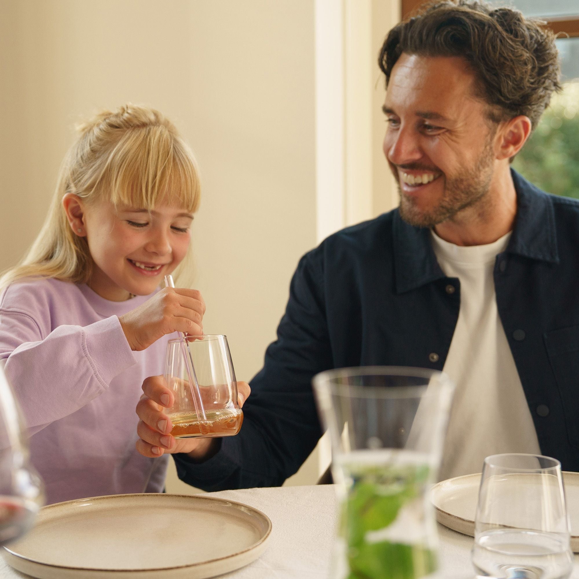 Ein Mann und ein Mädchen genießen Getränke mit Weißweingläsern Stölzle Lausitz am Tisch.